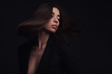 Portrait of a beautiful girl with flying brown hair over dark studio background