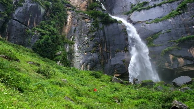 Alone trekker weared in red jacket near the Jogini waterfall, Manali, Himachal Pradesh, India