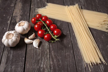 Cherry-tomatoes, spaghetti pasta, garlic, parmesan on wooden tab