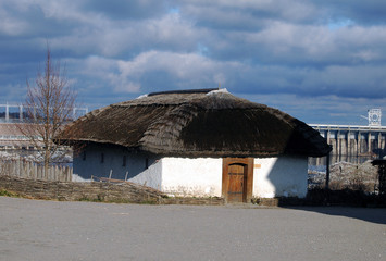 Fototapeta na wymiar Ukrainian historical hut with whiite wall, thatched roof and wooden door