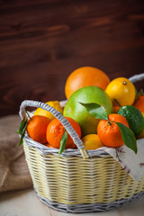 citrus fruits in a wicker basket on a wooden background