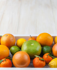 citrus fruits in a wooden box on a light wooden background