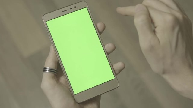 Man using smartphone with green screen. Close up shot hands with mobile, 4k ungraded footage shot in 24fps 