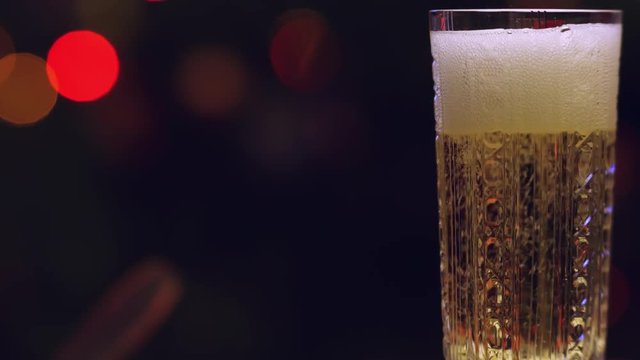 Filling a crystal glass of champagne on the background of blurred lights