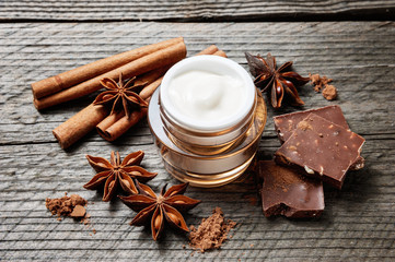 Chocolate skin treatment. Cosmetic jar with lotion, cocoa, anise, cinnamon sticks.
