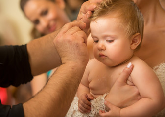 Mother with her baby at the christening ceremony in the church. Orthodox baptism in Greece