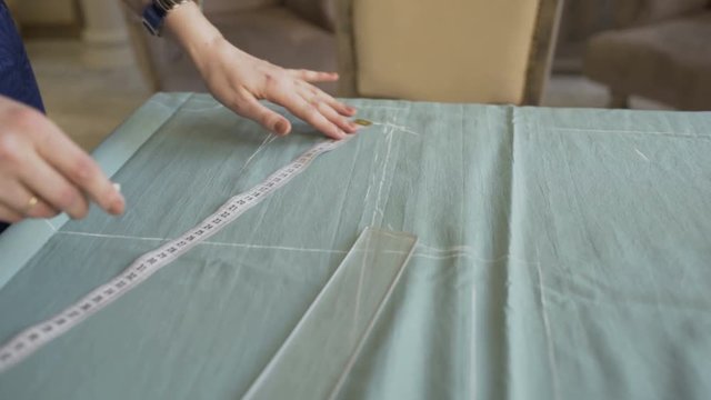 Seamstress and fashion designer at work. Young woman draw chock on the cloth in tailor studio