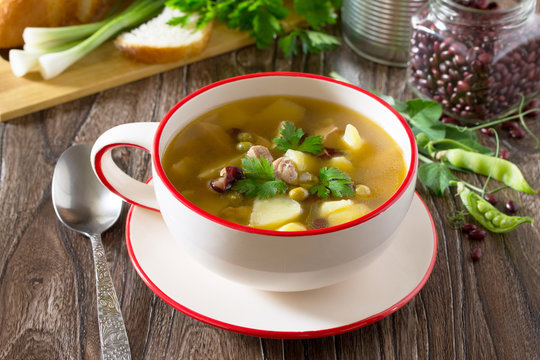Soup with meat, beans, green peas and fresh vegetables on a wood