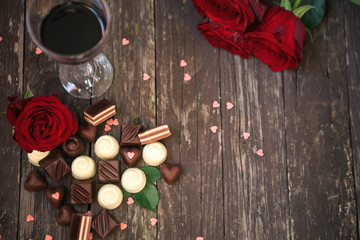 Old wooden background with red roses and chocolate pralines copy