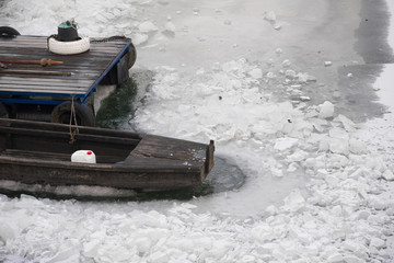 Wooden boat and dock in frozen river on cold winter day