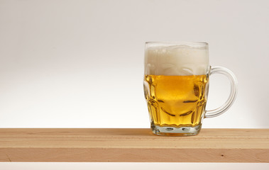 Glass of light beer on a wooden board.