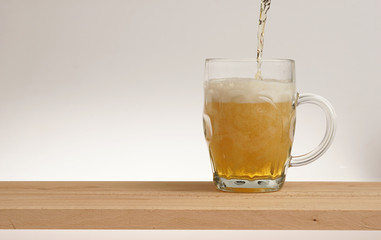 Glass of light beer on a wooden board.