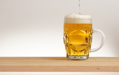 Mug of light beer on a wooden board.