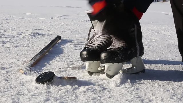 Man cleaning and taking hockey skates from snow