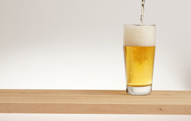 Glass of light beer on a wooden board.