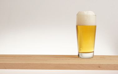 Glass of light beer on a wooden board.