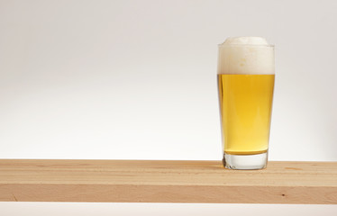 Glass of light beer on a wooden board.