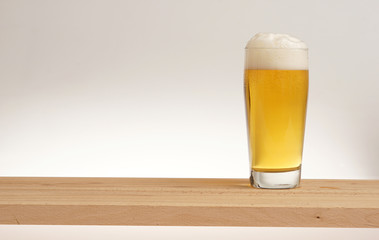 Glass of light beer on a wooden board.