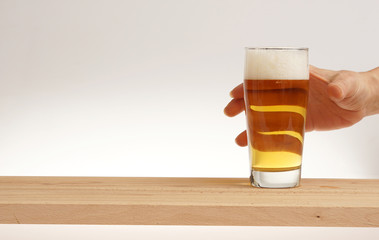 Hand take glass of light beer from wooden board.