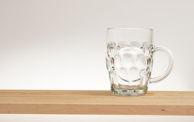 Empty mug of light beer on a wooden board.