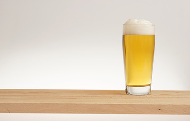 Glass of light beer on a wooden board.