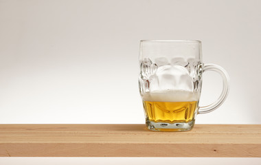 Mug of light beer on a wooden board.