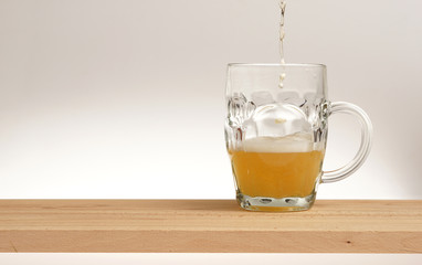Mug of light beer on a wooden board.