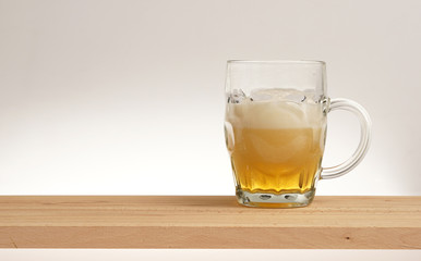 Mug of light beer on a wooden board.