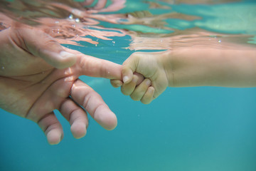 Baby and fathers hands in water