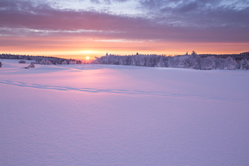 Wunderschöner Sonnenaufgang an einem kalten Wintertag im Erzgebirge mit einer kleinen Holzhütte im Hintergrund