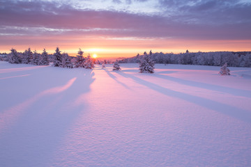 Wunderschöner Sonnenaufgang an einem kalten Wintertag im Erzgebirge mit einer kleinen Holzhütte im Hintergrund
