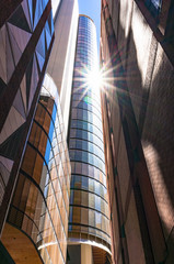 Modern skyscraper with sun flare, sun star reflected from the gl