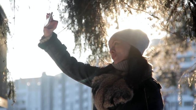 cheerful girl makes selfi during sunset in winter city
