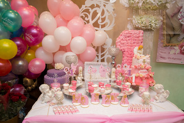 Sweet buffet on a pink table in a happy bersday party.