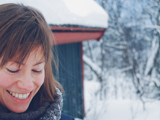 Young woman smiling broadly looking down in snowy landscape