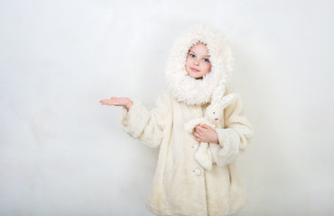 Obraz premium Beautiful little girl in winter clothes with a toy rabbit.