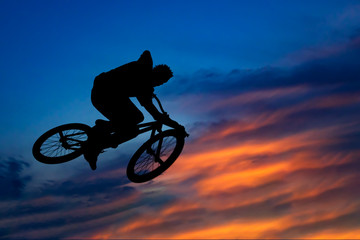 Obraz na płótnie Canvas Silhouette of a biker jumping against the beautiful sky at sunse