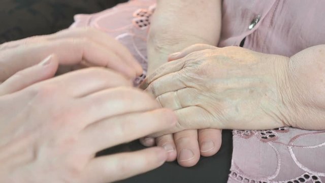Man strokes the old wrinkled woman's hands during a difficult situation. Close up
