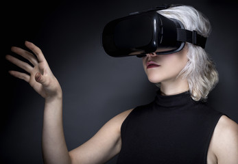 Woman wearing a virtual reality headset touching or holding something.  She is interacting with...