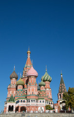 Fototapeta na wymiar St. Basil's Cathedral on Red Square showing decorative red brick facade and colorful onion domes topped with Orthodox crosses against a deep blue sky. 