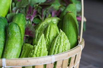 Tropical green organic vegetable on basket on wooden background