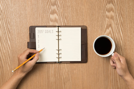 2017 Goals.. Top view of hand writing on a blank notebook with h