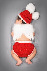Newborn baby dressed as red angel with wings