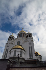 Church of All Saints, a Russian Orthodox Church built of the site of the Romanovs' execution in Yekaterinburg. The church has a white facade and golden onion domes topped with crosses.
