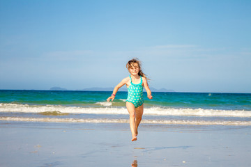 Fototapeta na wymiar young happy child girl having fun on sand beach, sea background