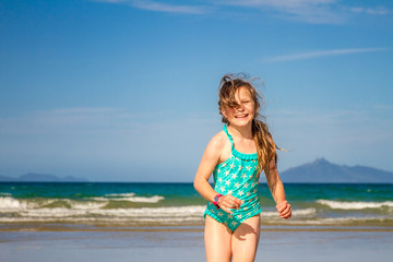 Naklejka premium young happy child girl having fun on sand beach, sea background