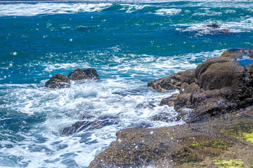 The waves breaking on a stony beach, forming a spray
