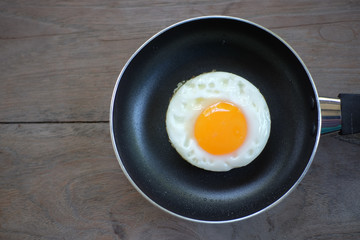 fried egg with pan on wood floor