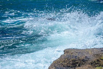 Obraz premium The waves breaking on a stony beach, forming a spray