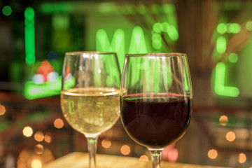 Red and white wine glasses on blurred lights background